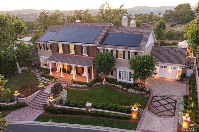 view of front of home with solar panels, a porch, a front lawn, and a garage