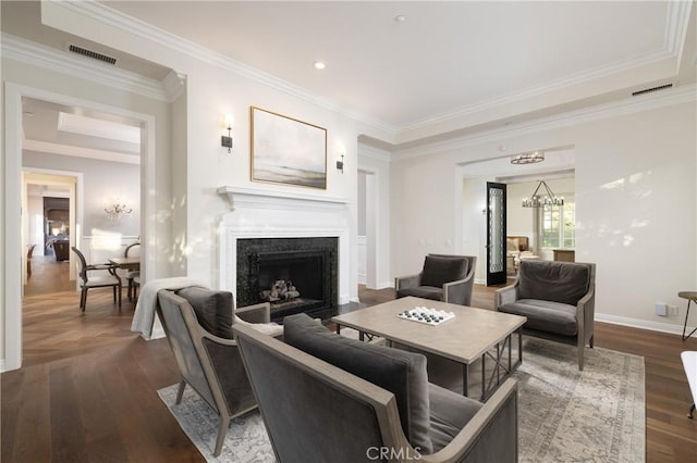 living room featuring a chandelier, a premium fireplace, crown molding, and dark wood-type flooring