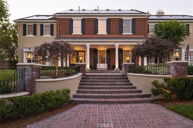 colonial inspired home with solar panels and a porch