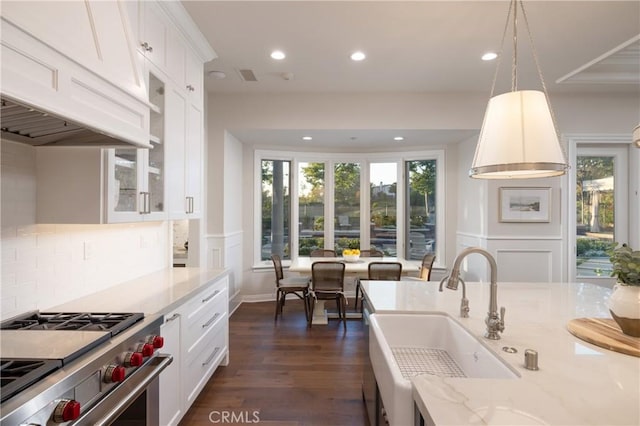 kitchen featuring white cabinets, decorative light fixtures, and high end stainless steel range