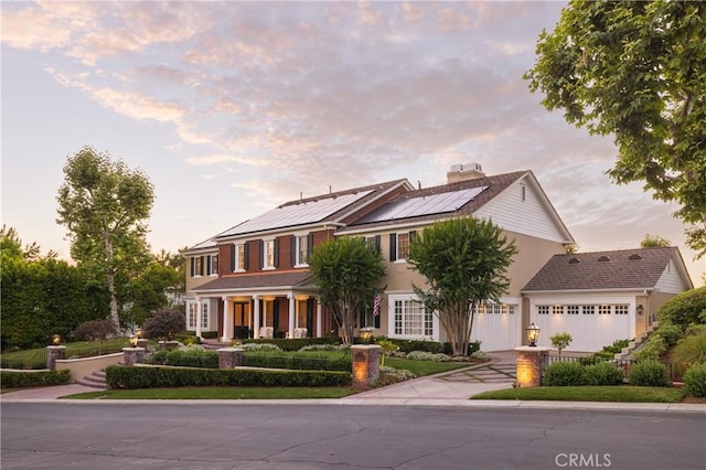 colonial house featuring solar panels and a garage