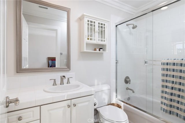 full bathroom featuring crown molding, vanity, bath / shower combo with glass door, and toilet