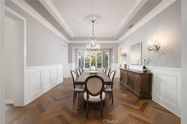 dining room with dark parquet flooring, a tray ceiling, crown molding, and a notable chandelier