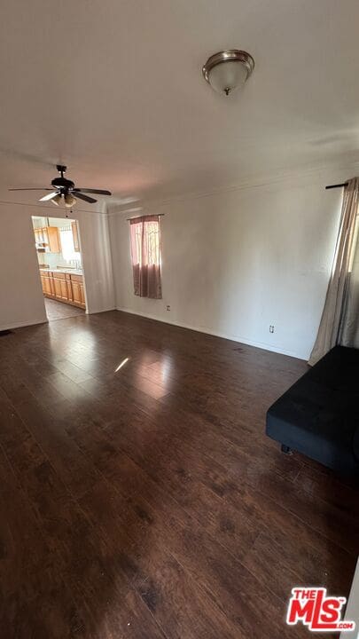 unfurnished living room with dark wood-type flooring and ceiling fan