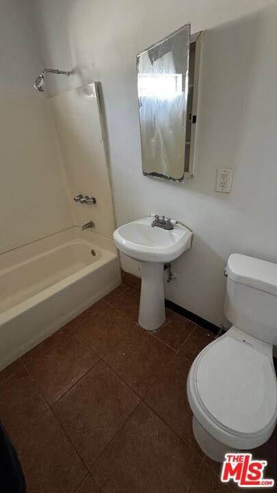 bathroom with tile patterned flooring, tub / shower combination, and toilet