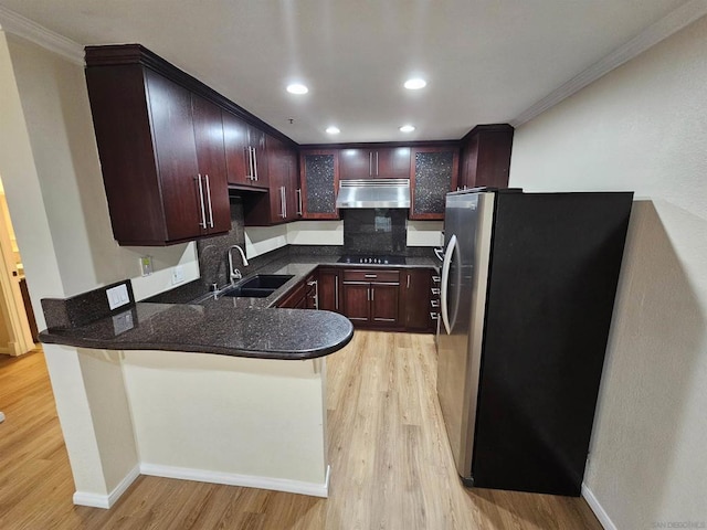 kitchen with kitchen peninsula, decorative backsplash, sink, stainless steel refrigerator, and crown molding