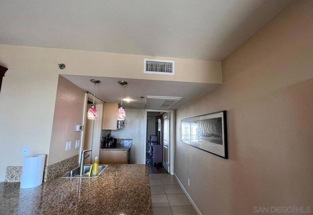 kitchen featuring light tile patterned flooring, sink, kitchen peninsula, decorative light fixtures, and vaulted ceiling