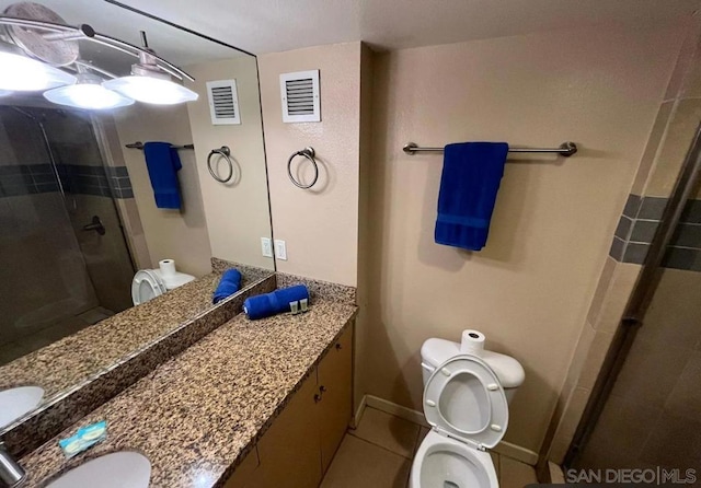 bathroom featuring vanity, toilet, tile patterned floors, and a shower with door