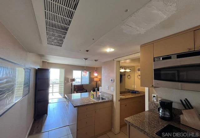 kitchen featuring hanging light fixtures, sink, kitchen peninsula, a textured ceiling, and light hardwood / wood-style floors