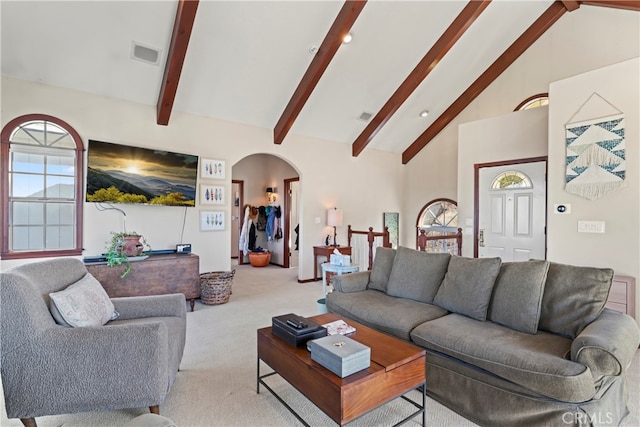 carpeted living room with high vaulted ceiling and beam ceiling