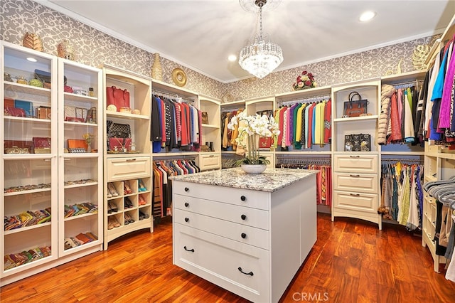 spacious closet with an inviting chandelier and dark hardwood / wood-style floors