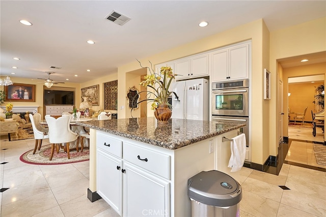 kitchen with white cabinets, ceiling fan, double oven, and a kitchen island