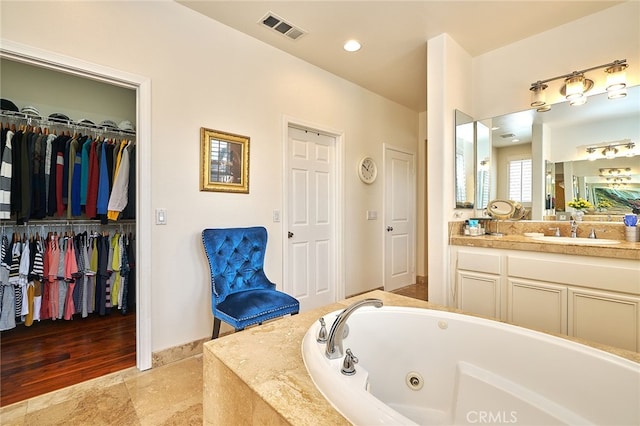 bathroom with hardwood / wood-style floors, tiled tub, and vanity