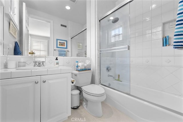 full bathroom with combined bath / shower with glass door, vanity, toilet, and tile patterned flooring