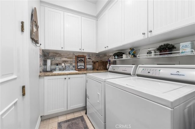 laundry area with washer and dryer, light tile patterned flooring, cabinets, and sink