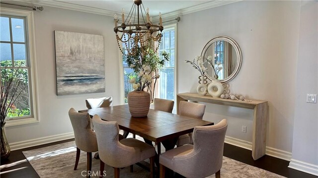 dining room with dark hardwood / wood-style floors, a healthy amount of sunlight, ornamental molding, and an inviting chandelier