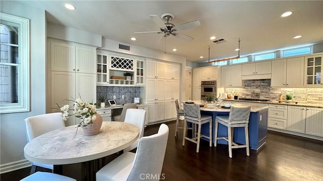 kitchen with visible vents, glass insert cabinets, dark wood-style flooring, and a center island