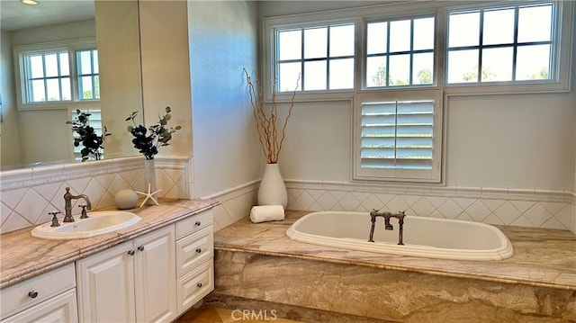 bathroom featuring backsplash, a garden tub, and vanity