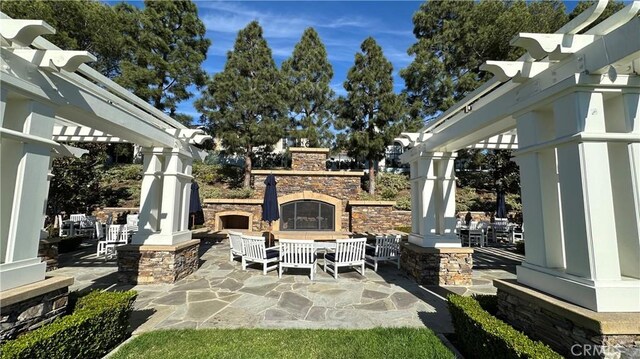 view of patio featuring a pergola and an outdoor stone fireplace