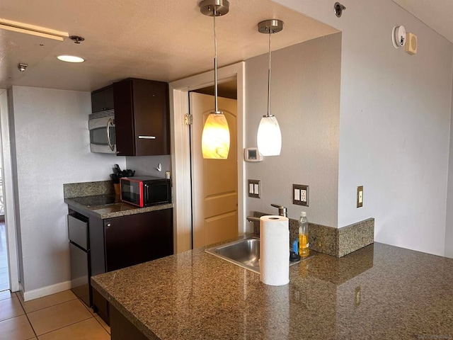 kitchen featuring light tile patterned flooring, dark brown cabinets, sink, and decorative light fixtures