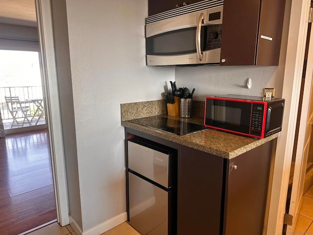 kitchen featuring dark brown cabinets, light wood-type flooring, and black appliances