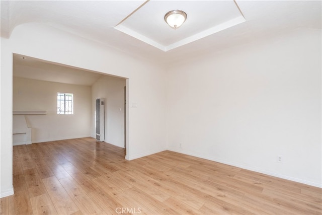 unfurnished room with light hardwood / wood-style floors and a raised ceiling