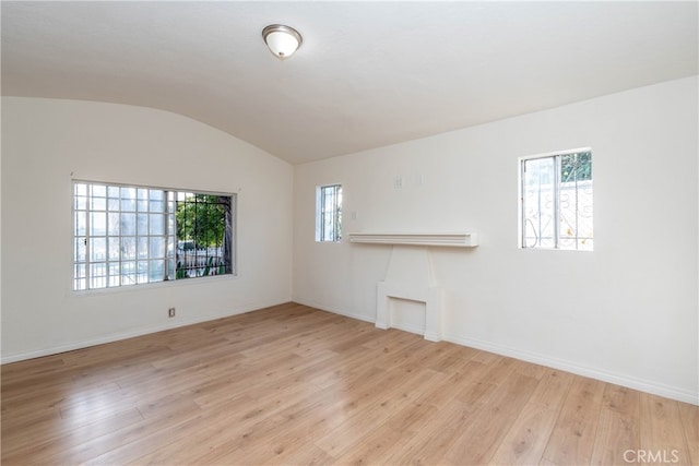 spare room with vaulted ceiling and light hardwood / wood-style floors