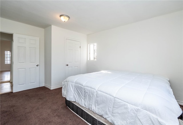 bedroom featuring dark carpet and multiple windows