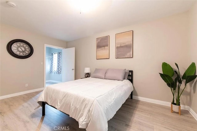 bedroom featuring ensuite bathroom and light wood-type flooring