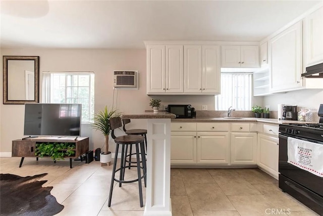 kitchen featuring a wall mounted air conditioner, black appliances, white cabinets, sink, and a kitchen bar