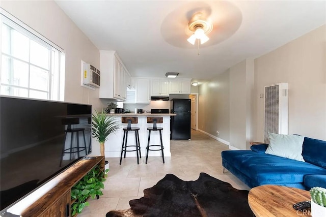 living room with ceiling fan, light tile patterned floors, and a wall unit AC