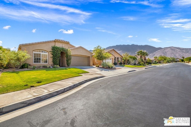 view of front of house with a garage, a mountain view, and a front yard