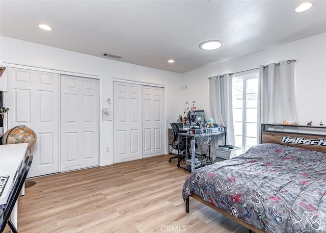 bedroom with two closets and light hardwood / wood-style floors