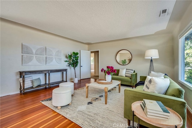 living room with wood-type flooring and a textured ceiling