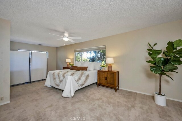 carpeted bedroom with ceiling fan and a textured ceiling