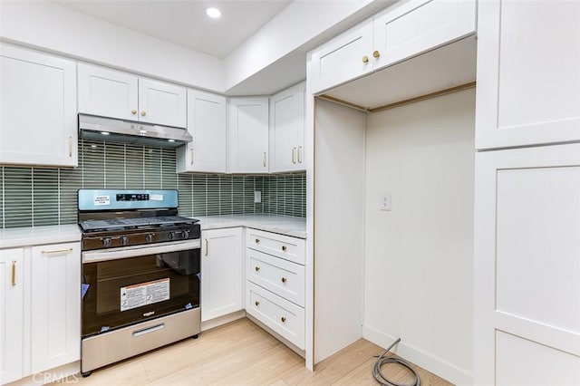 kitchen featuring white cabinetry, backsplash, stainless steel range oven, and light wood-type flooring