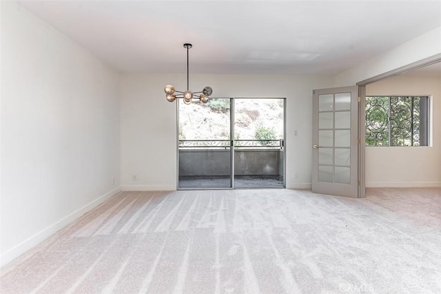 carpeted spare room featuring an inviting chandelier and a wealth of natural light