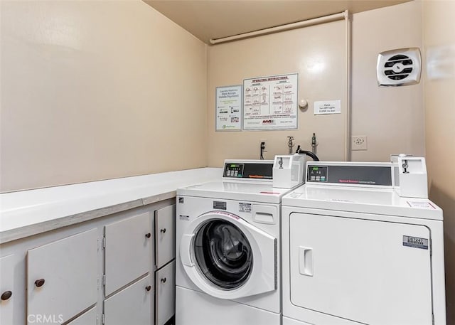 clothes washing area with cabinets and washing machine and clothes dryer