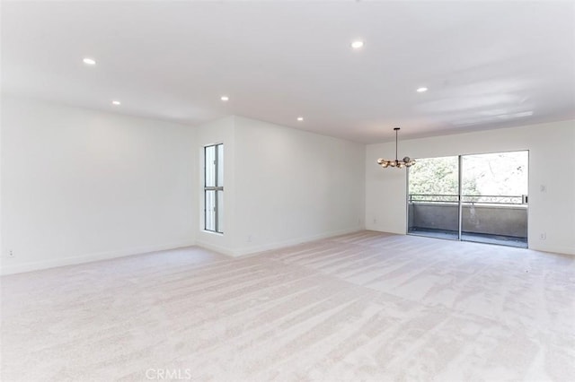 unfurnished room with a notable chandelier and light colored carpet