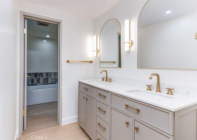 bathroom featuring hardwood / wood-style flooring, a tub to relax in, and vanity