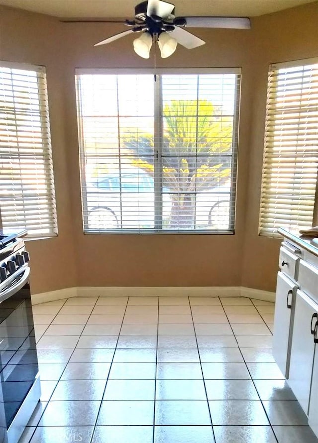 kitchen with stainless steel range, white cabinetry, ceiling fan, and light tile patterned flooring