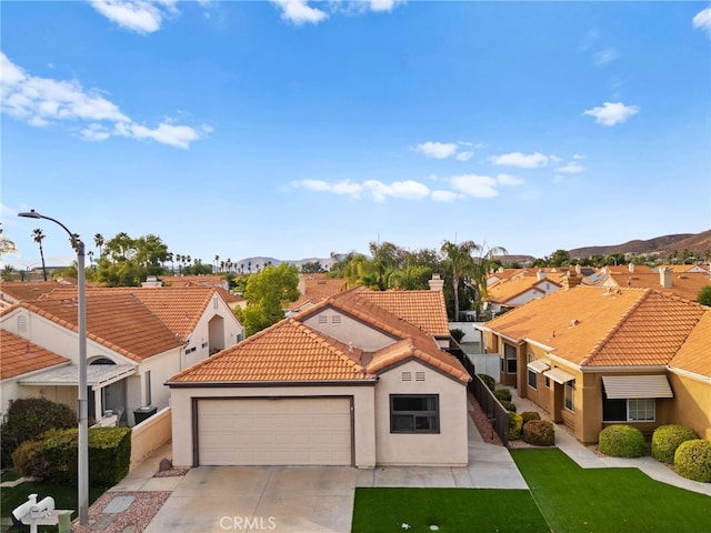 mediterranean / spanish-style home featuring a mountain view, a garage, and a front lawn