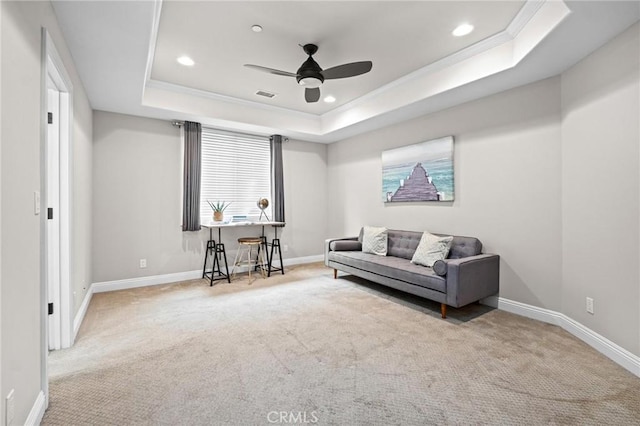 living area featuring a raised ceiling, crown molding, carpet flooring, and ceiling fan