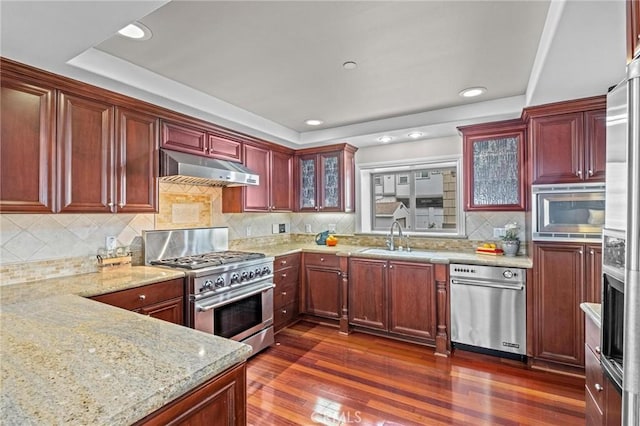 kitchen with tasteful backsplash, dark hardwood / wood-style floors, sink, light stone countertops, and stainless steel appliances