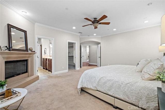 carpeted bedroom with connected bathroom, a walk in closet, ornamental molding, and ceiling fan