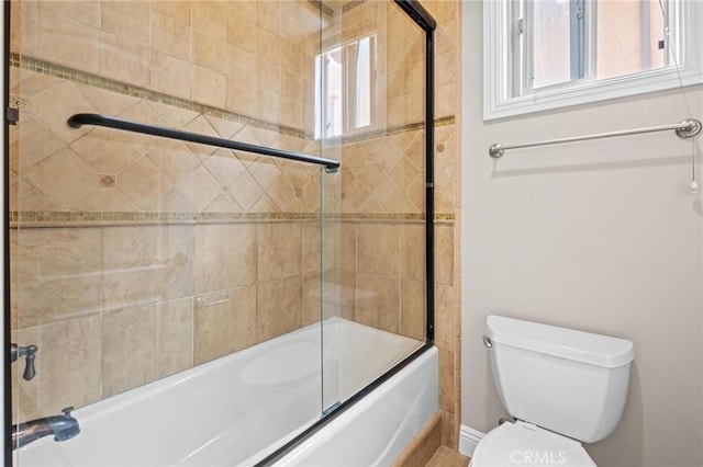 bathroom featuring enclosed tub / shower combo and toilet