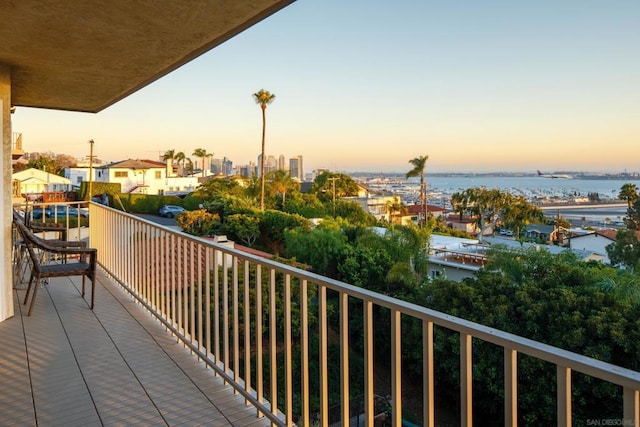 balcony at dusk featuring a water view