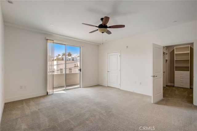 unfurnished bedroom featuring light carpet, a walk in closet, access to outside, and ceiling fan