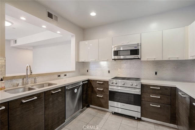 kitchen featuring sink, light tile patterned flooring, dark brown cabinets, stainless steel appliances, and white cabinets