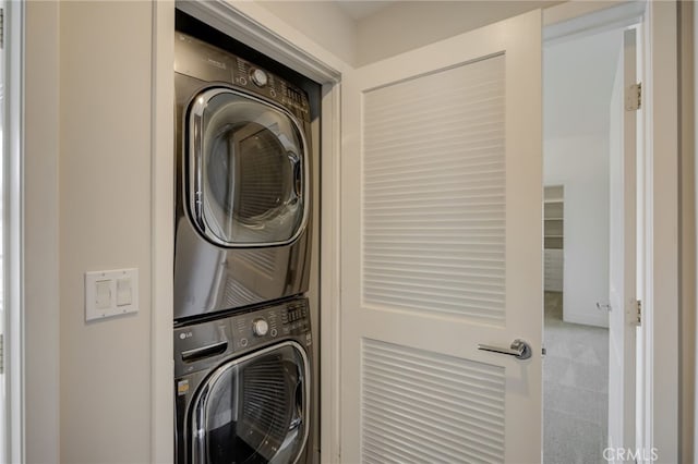 clothes washing area featuring stacked washing maching and dryer and carpet floors